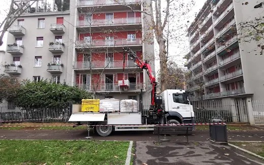 Autocarro con gru di Centro Edile 3.0 durante la consegna di materiali edili in un cortile condominiale